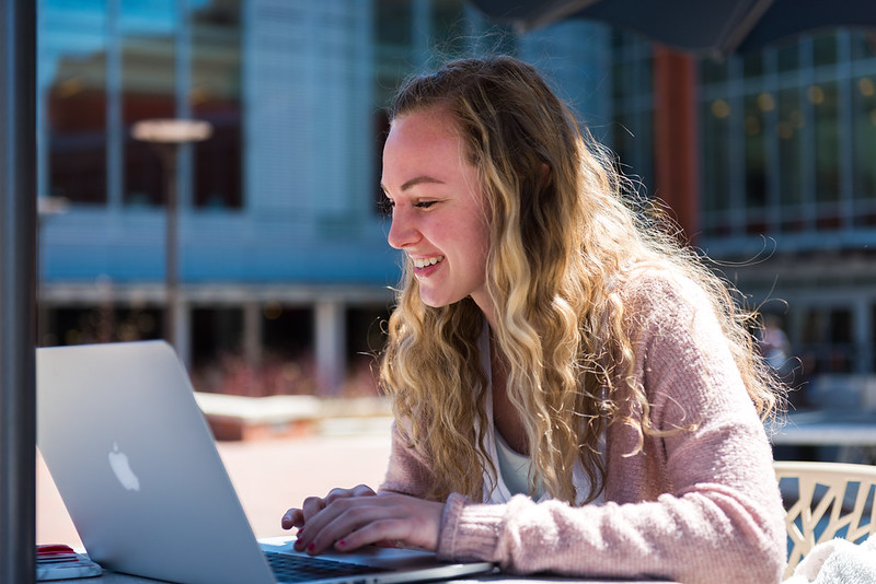 A student works on a laptop outdoors.