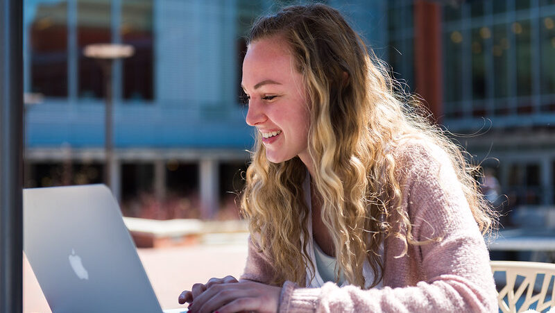 A student works on a laptop outdoors.